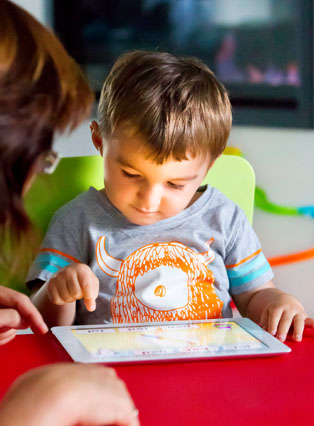 Child playing PLD game on iPad together with adult